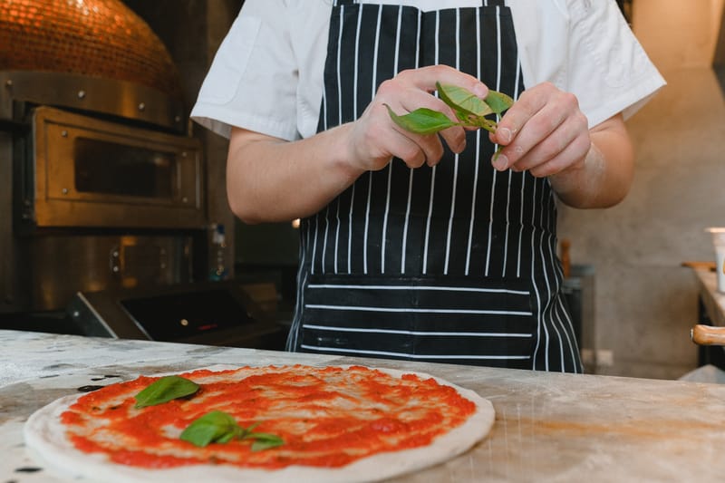 Round table pizza chefs crafting fresh pizzas with quality ingredients